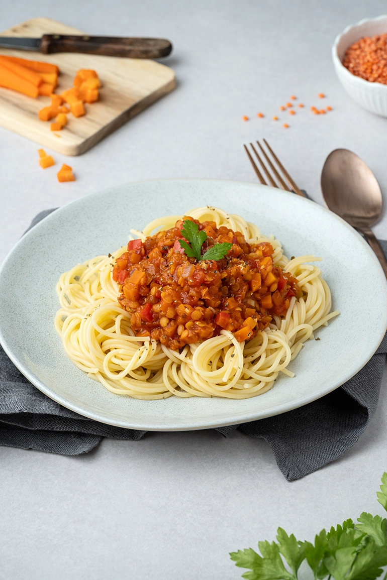vegan_rezept_Linsen_Bolognese_1 Ein Teller mit Spaghetti und Linsen-Bolognese auf hellem Untergrund