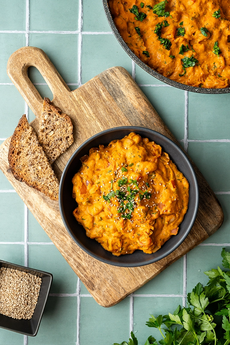 vegan_rezept_vegane_Bohnenpfanne_4 vegane cremige Tomaten-Bohnen-Pfanne in einer schwarzen Schale auf einem Holzbrett