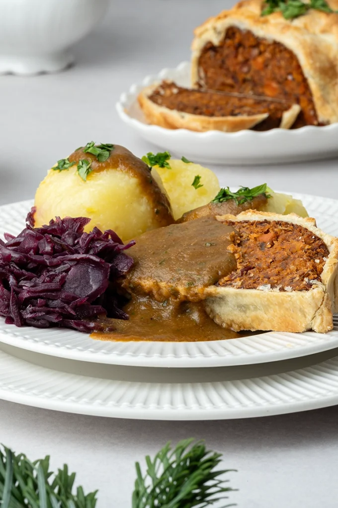 Vegane Bratensoße über einer Scheibe Nussbraten mit Rotkohl und Klößen