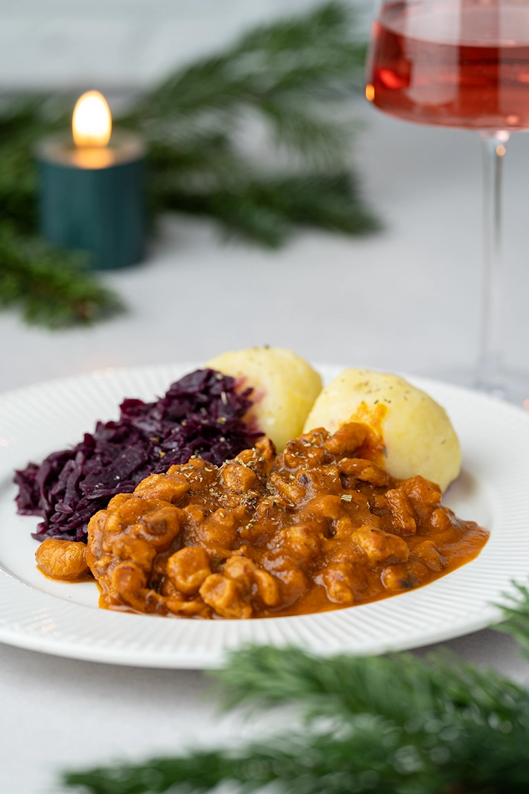 vegan_rezept_veganes_Gulasch_1 veganer Gulasch mit Rotkohl und Klößen auf einem weißen Teller