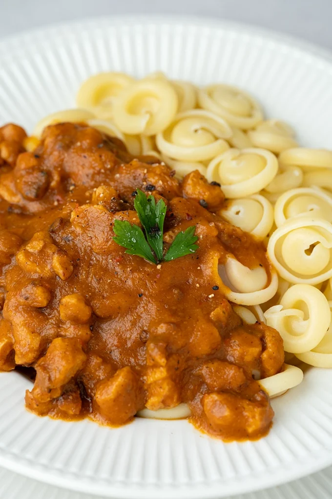 veganes Gulasch mit Nudeln auf einem weißen Teller