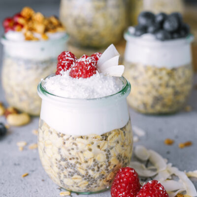 mehrere overnight oat mit Toppings wie Himbeeren, Balubeeren und Kokos