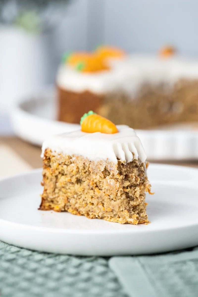 rezept-vegan-ostern-moehrenkuchen-karottenkuchen-1 Ein Stück Möhrenkuchen vegan auf weißem Teller