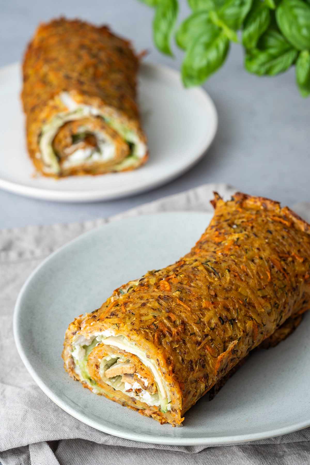 rezept-vegan-kartoffelrolle-gesundes-fastfood zwei Kartoffelrollen auf zwei Tellern auf hellem Untergrund