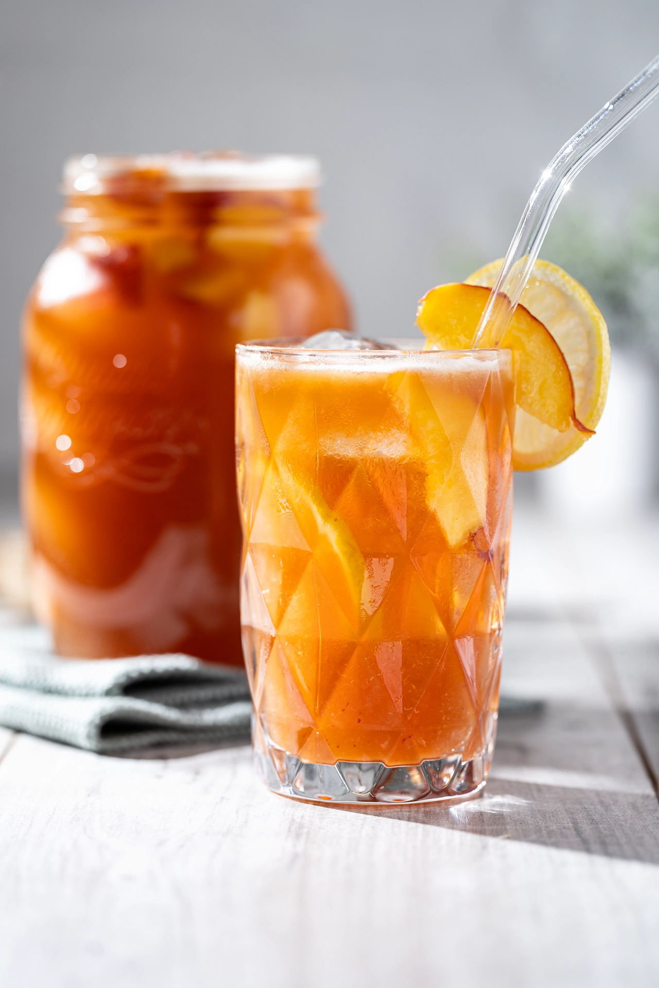 Selbstgemachter Pfirsich-Eistee - zuckerfrei, gesund und lecker 1 selbstgemachter Pfirsich-Eistee im Glas mit Strohhalm