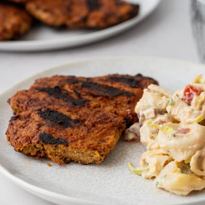 Vegane Steaks aus Seitan angeschnitten mit Tortellinisalat auf hellem Teller