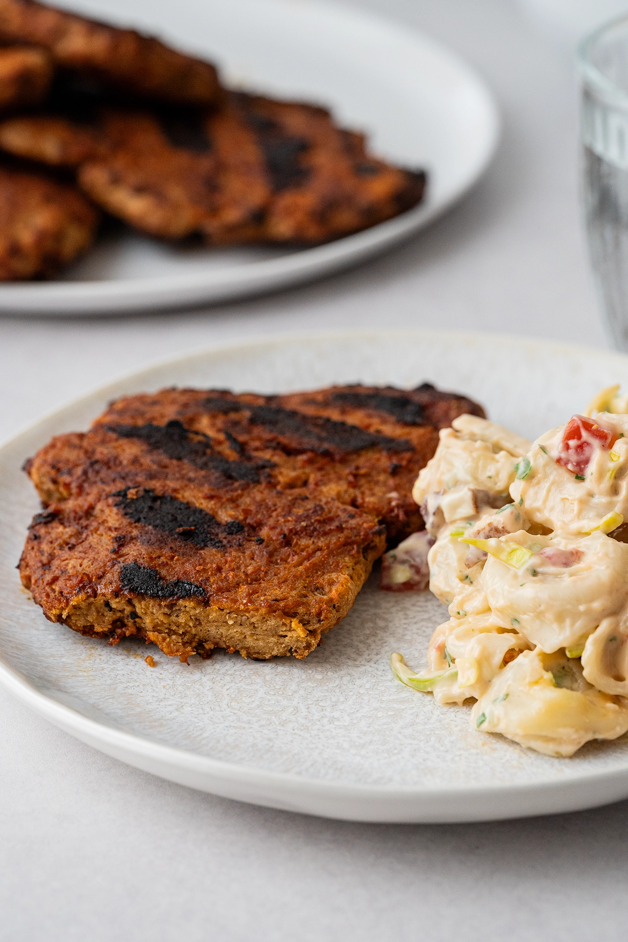 Vegane Steaks aus Seitan - proteinreich und perfekt zum Grillen 3 Vegane Steaks aus Seitan angeschnitten mit Tortellinisalat auf hellem Teller