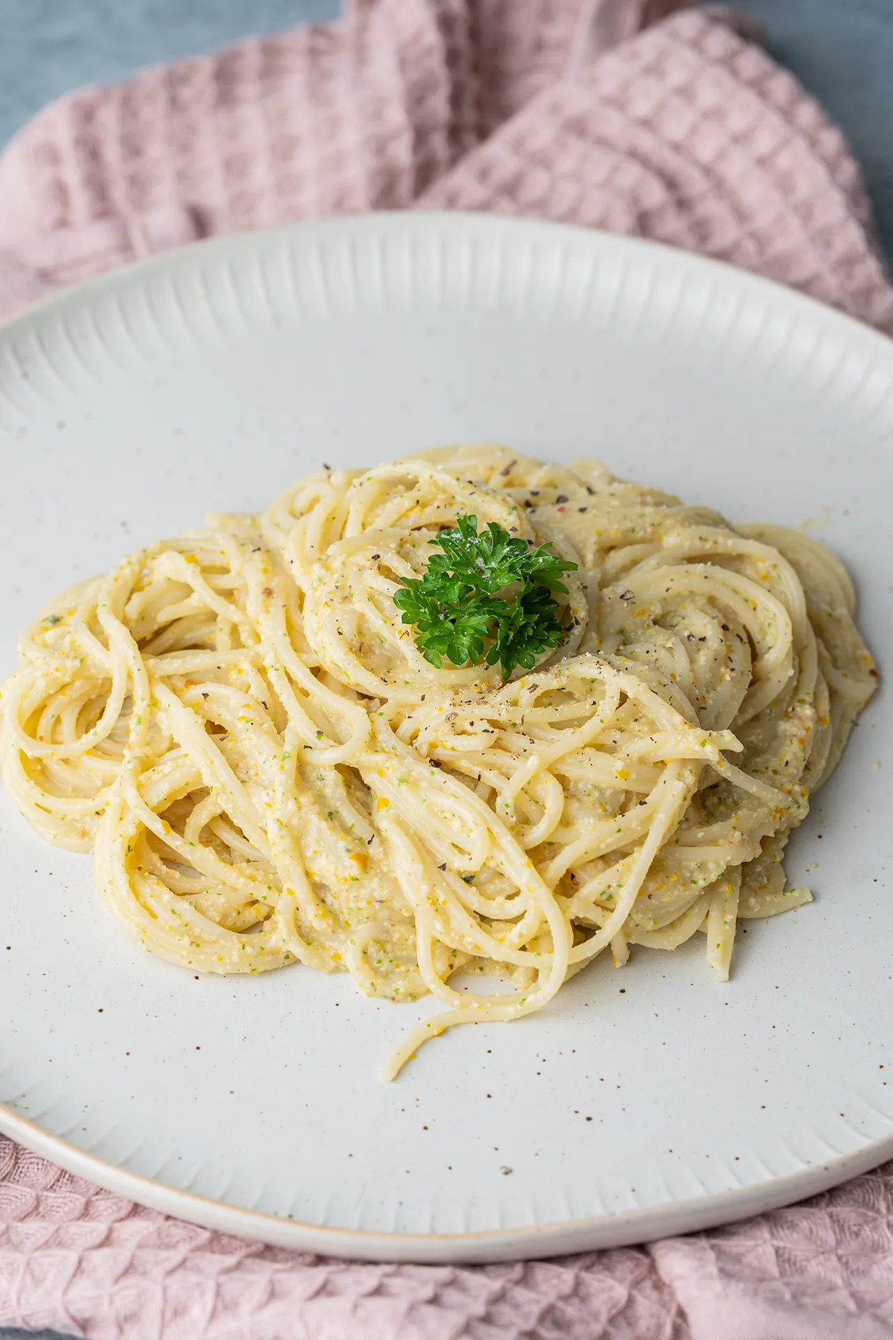 Spaghetti mit cremiger Zucchini Pest auf einem hellen Teller mit Petersiliendeko