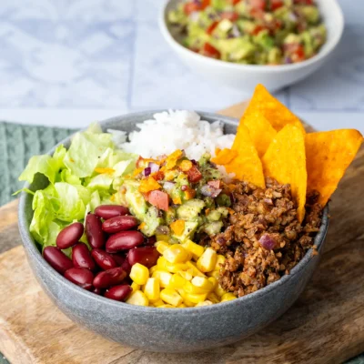 Mexican Bowl mit Guacamole in einer grauen Schale auf einem Brett