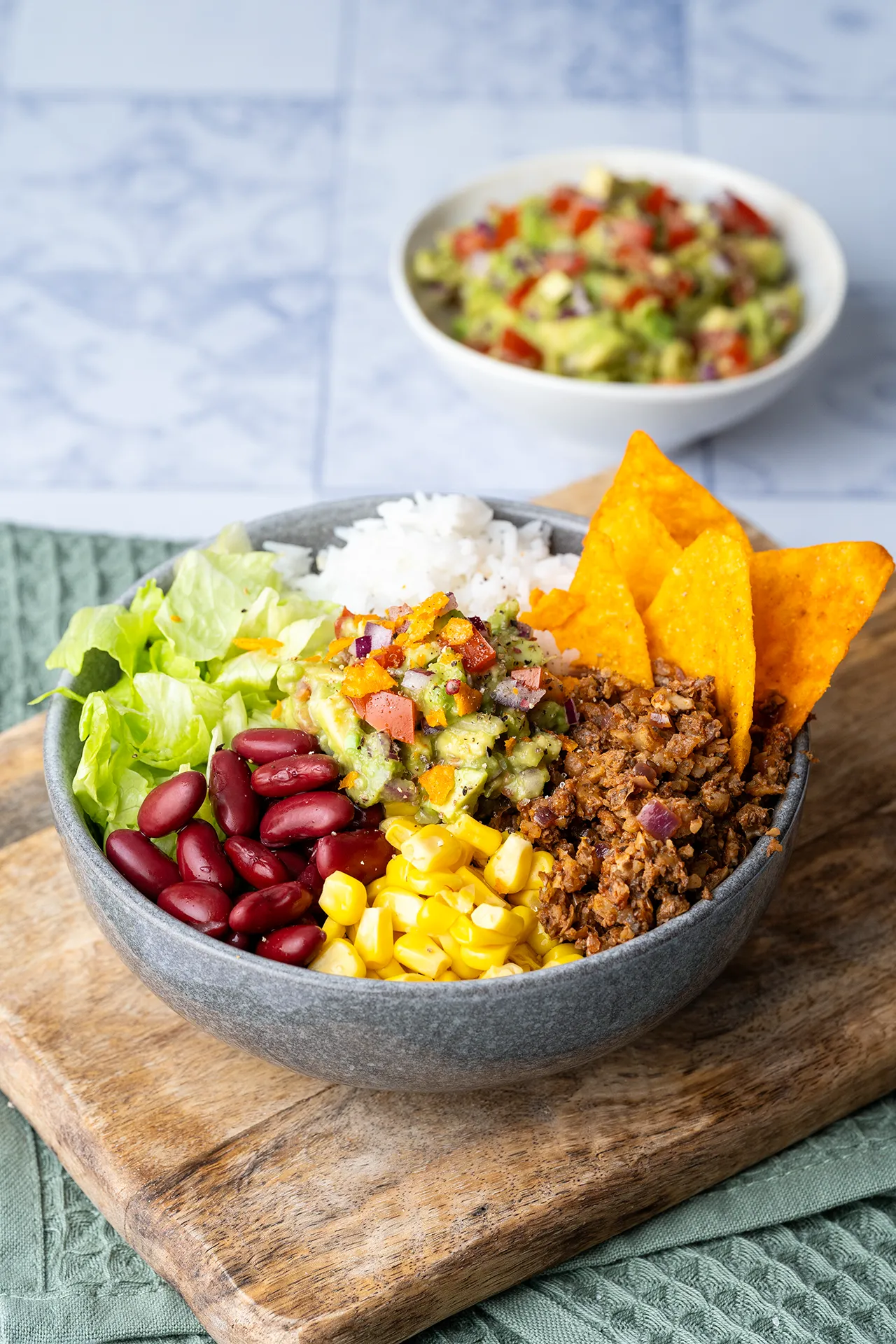 Burrito Bowl mit Guacamole 4 Mexican Bowl mit Guacamole in einer grauen Schale auf einem Brett