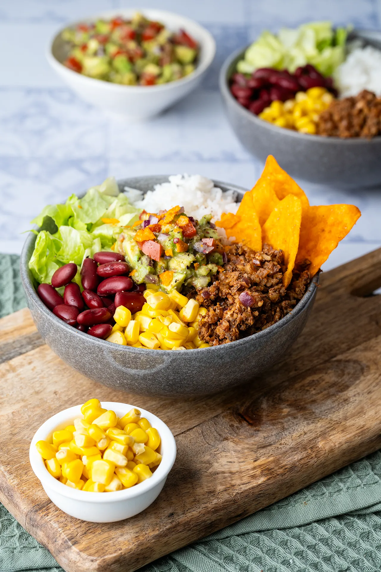 Burrito Bowl mit Guacamole 3 Mexican Bowl im Burrito Style mit Mais und Bohnen in dunkler Schale auf einem Brett