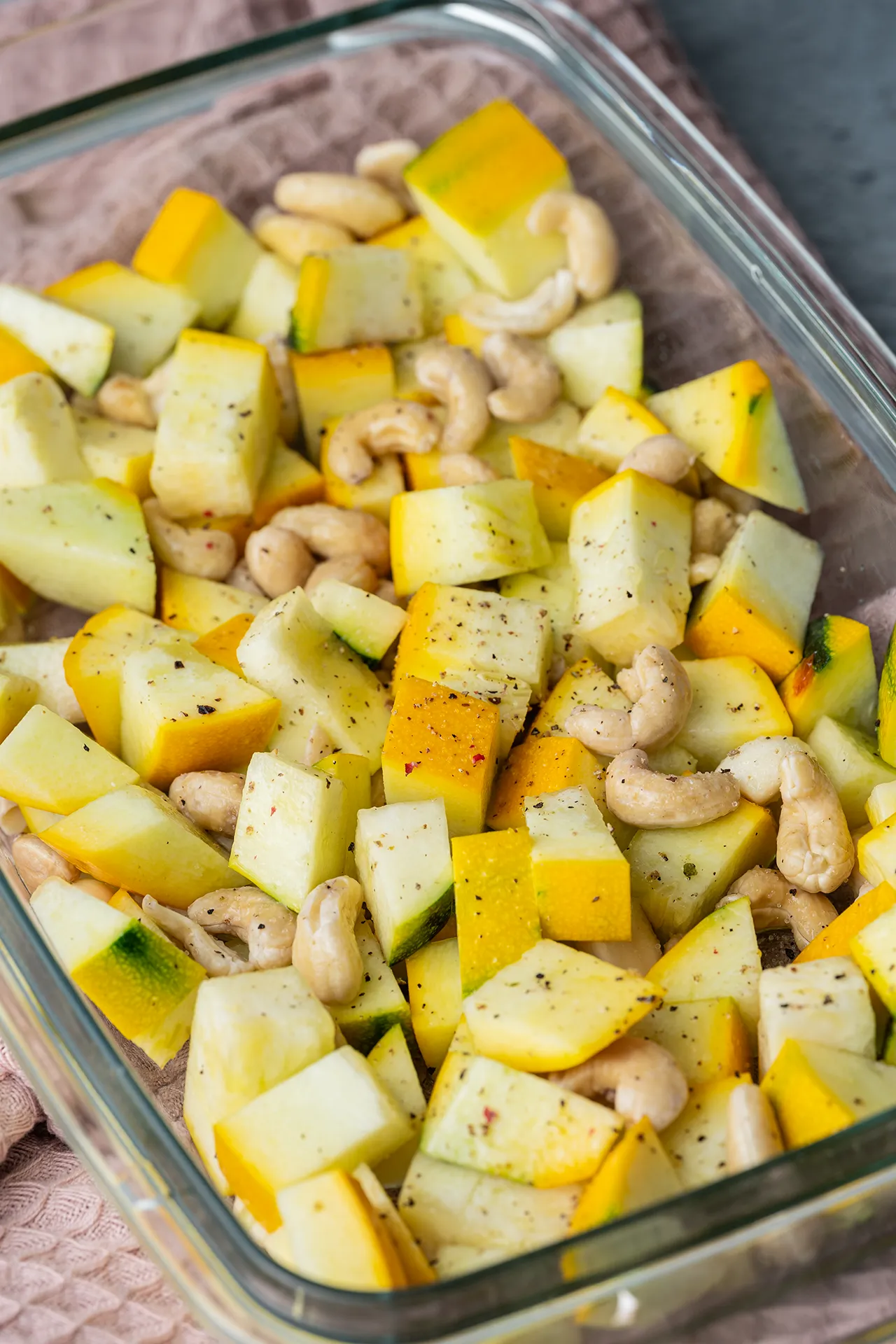 Gewürfelte rohe Zucchini mit Cashewkernen in einer Auflaufform