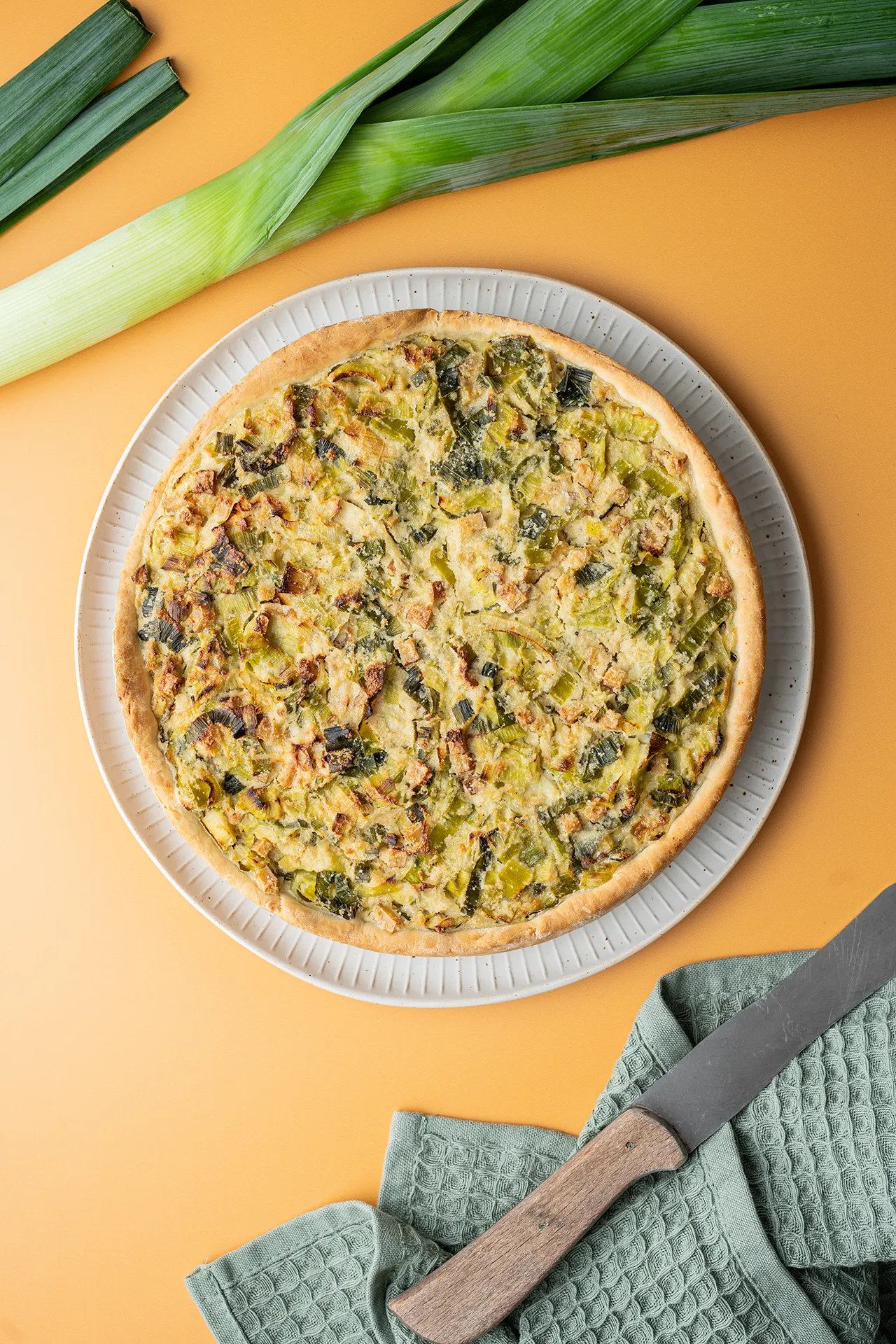 Veganer Lauchkuchen – herzhaft, einfach und richtig lecker 1 Veganer Lauchkuchen mit Hefeteig und Räcuhertofu auf orangenem Untergrund