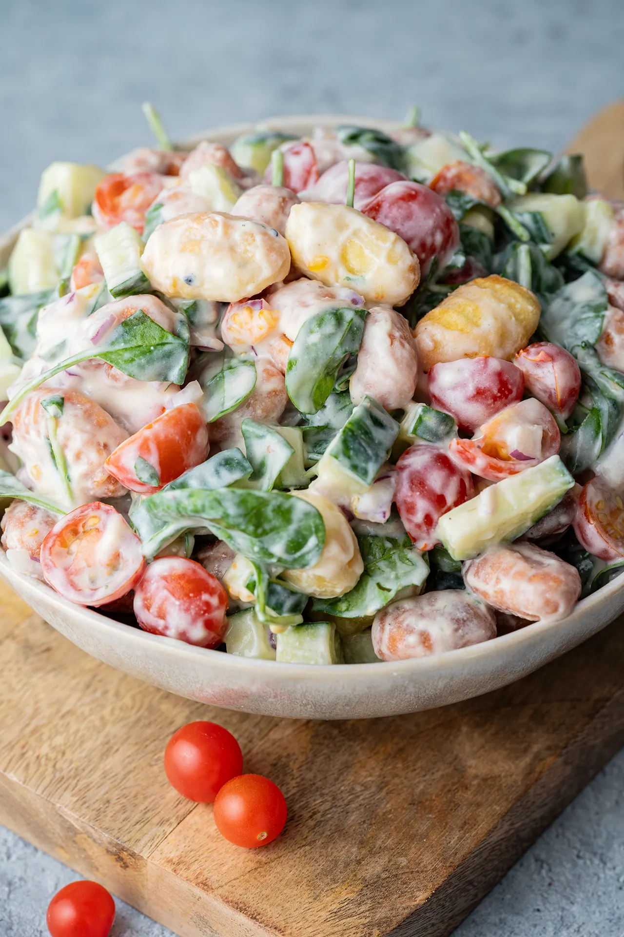 Knuspriger Gnocchi Salat mit Tomaten, Gurke und Spinat in einer hellen Schale