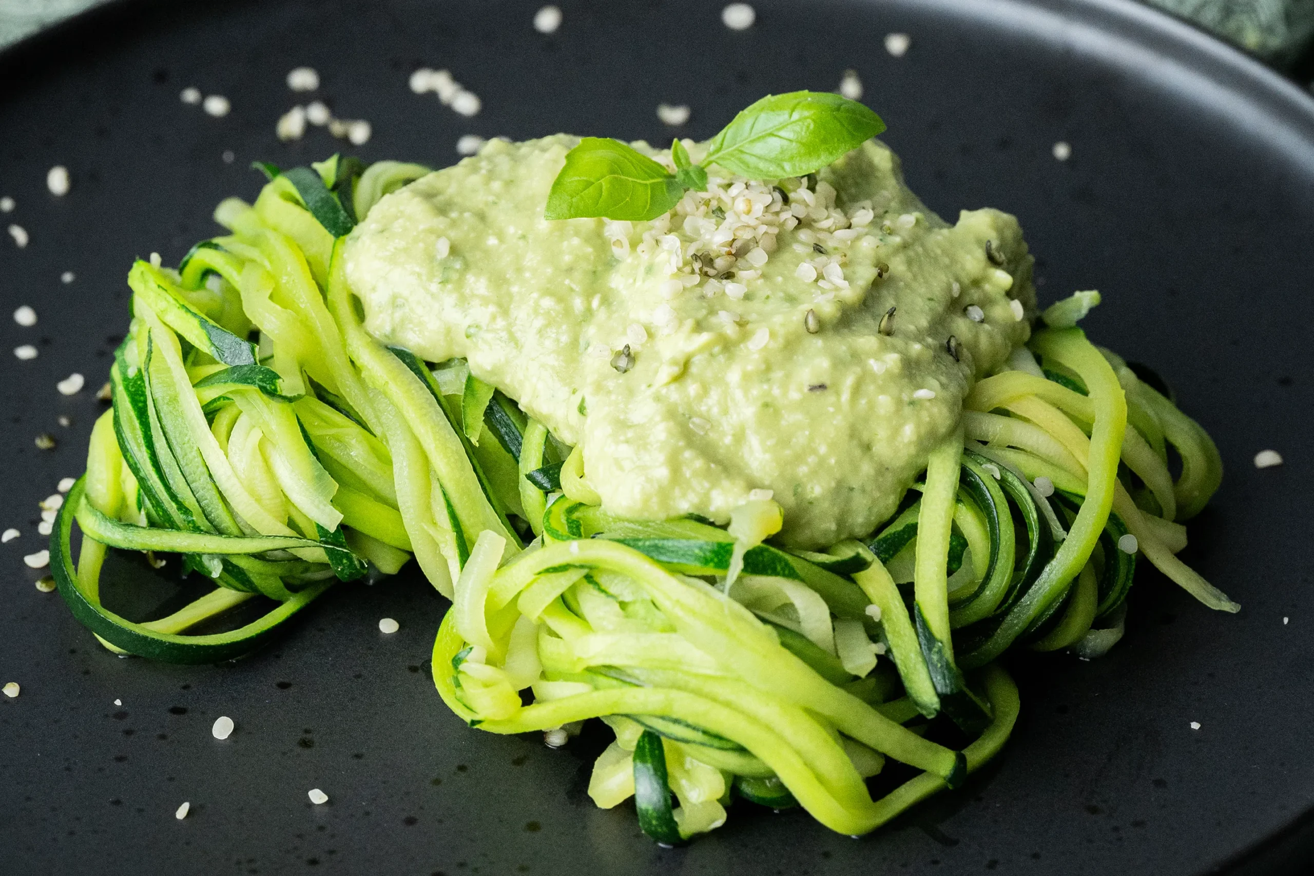 Zoodles mit Avocado-Pesto auf schwarzem Teller