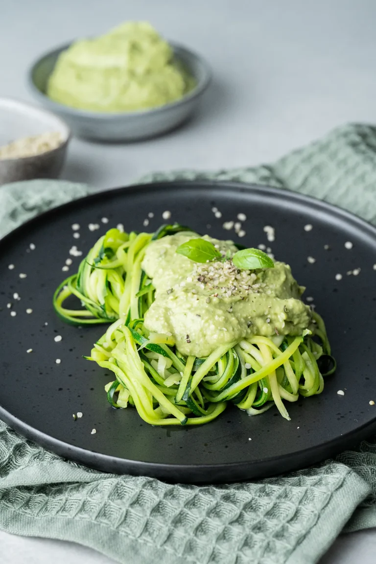 Zucchinispaghetti mit Avocado-Pesto und einem Blatt Basilikum