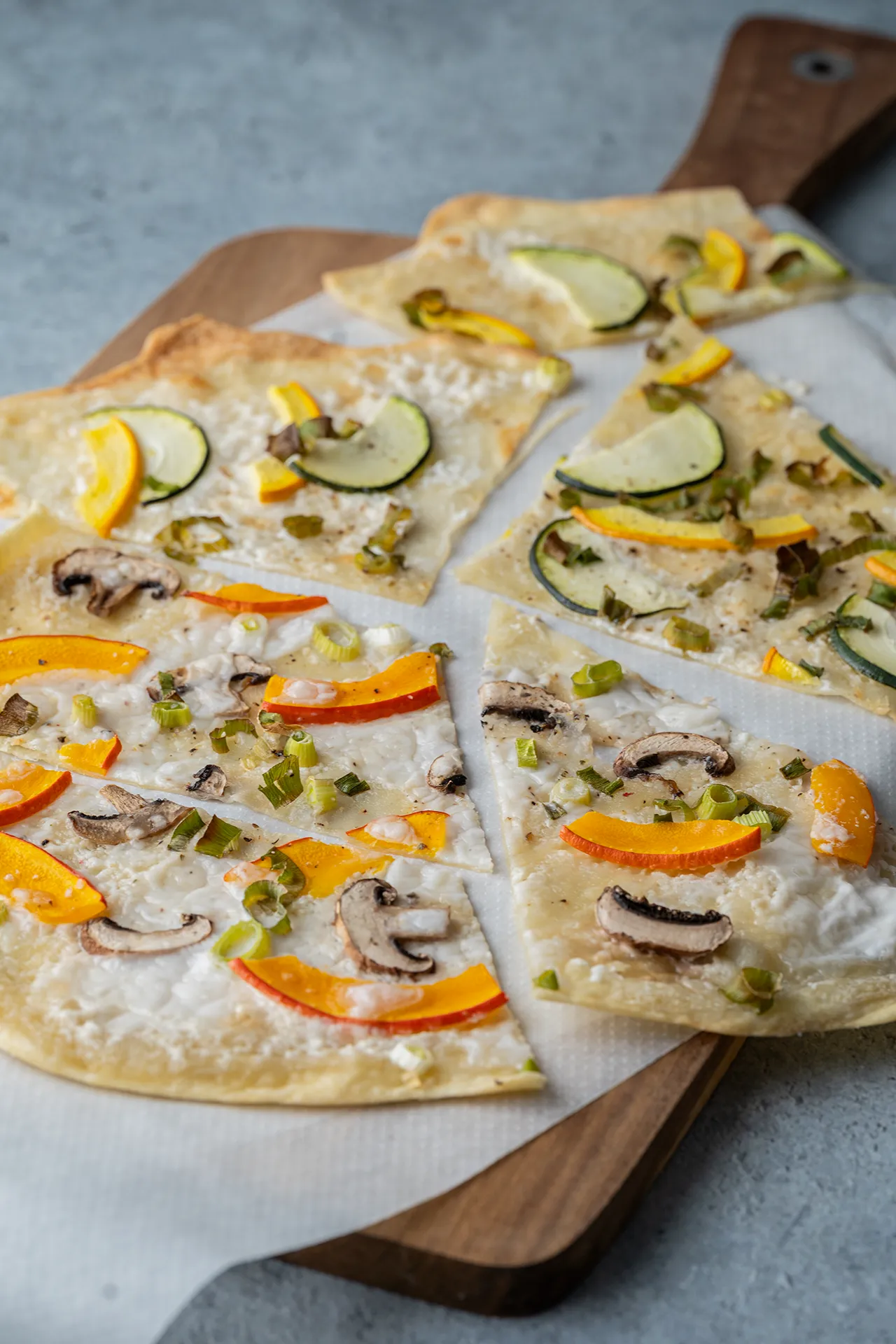 Einfacher veganer Flammkuchen - nach "veganer Elsässer Art" 1 Veganer Flammkuchen mit Kürbis und Zwiebeln geschnitten auf einem Brett