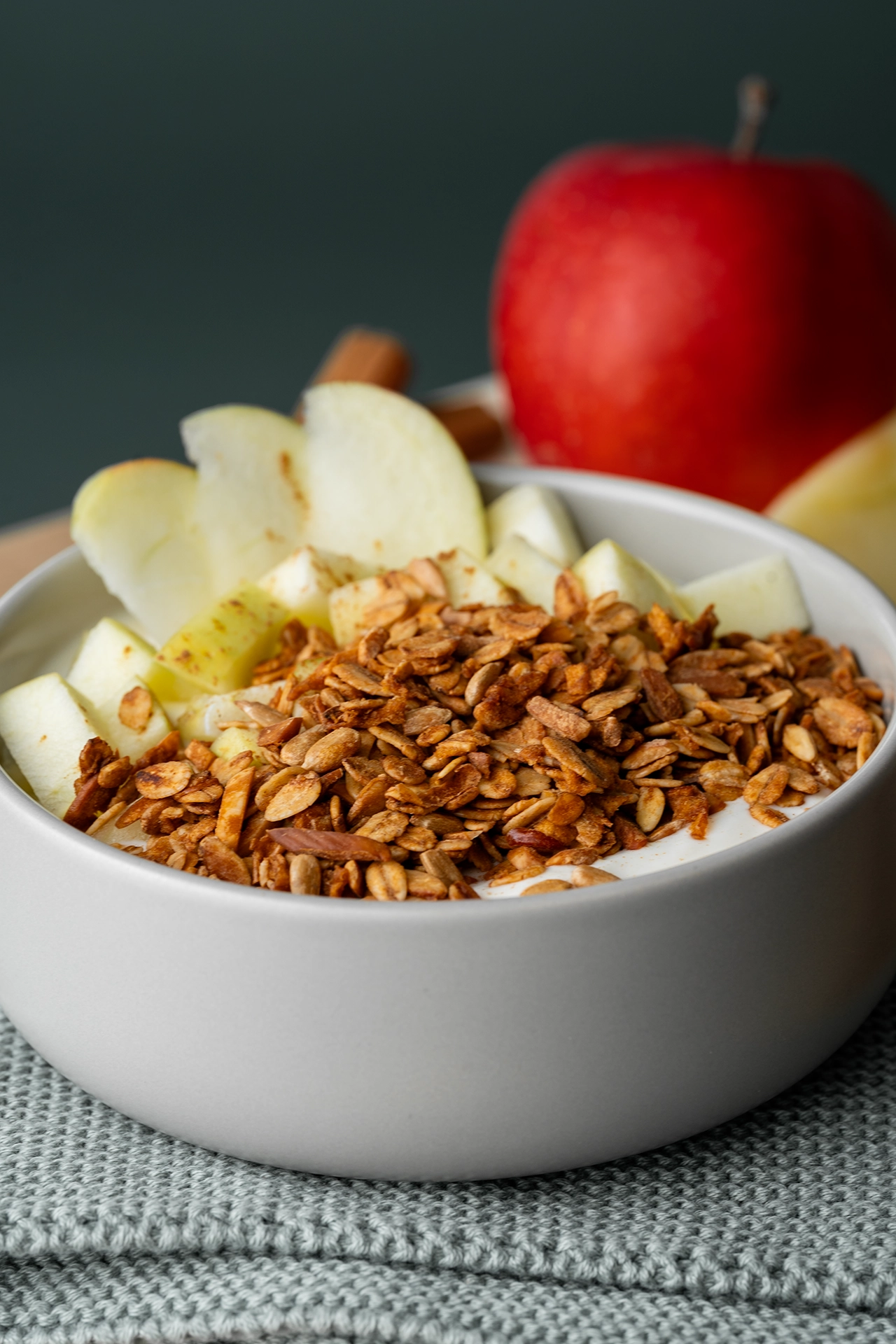 Eine Schale Joghurt mit Apfel und Granola auf grünem Grund