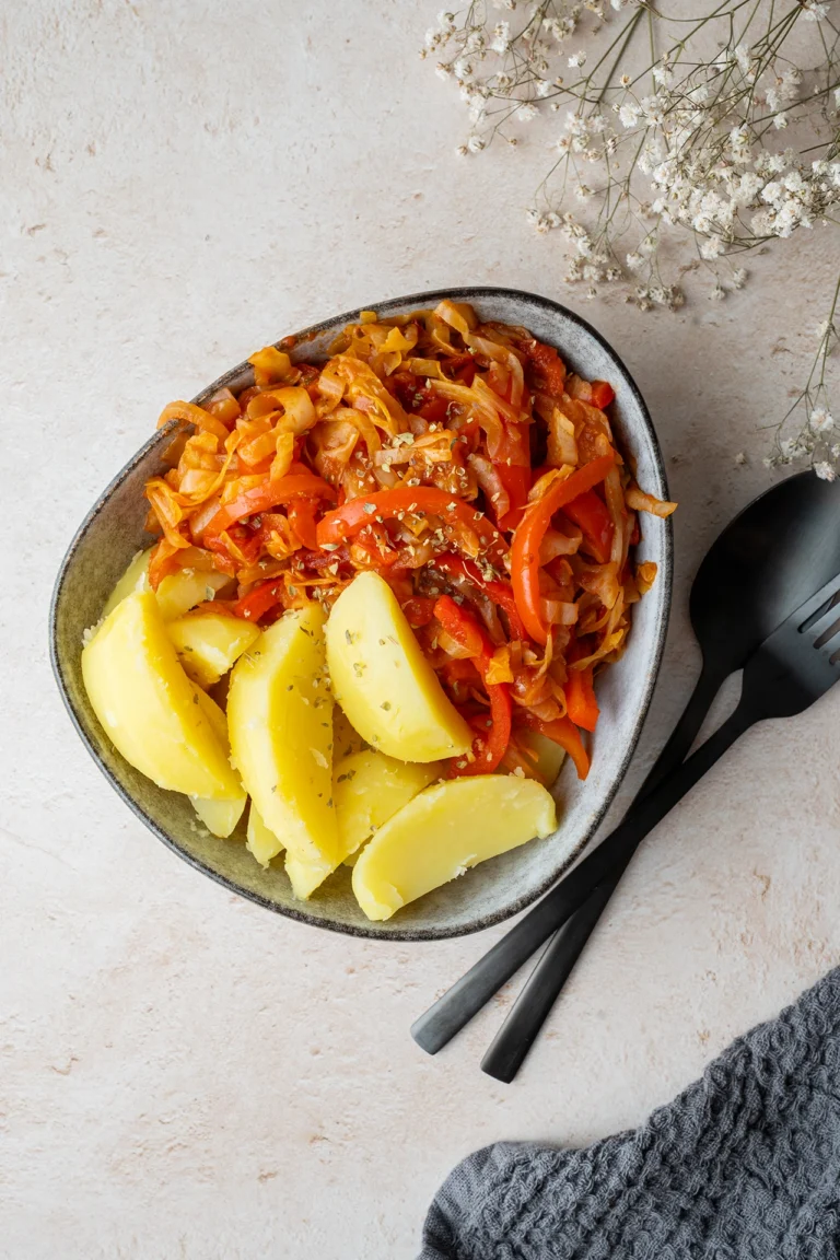 rezept-vegan-paprika-spitzkohl-pfanne Spitzkohl-Pfanne mit Kartoffeln in einer Schale daneben schwarzes Besteck