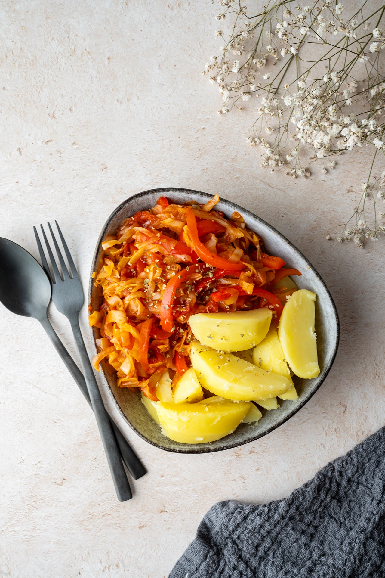 Einfache Spitzkohl-Pfanne mit Paprika 4 dunkles Besteck und Schale mit kortoffeln und Spitzkohlpfanne auf hellem Grund