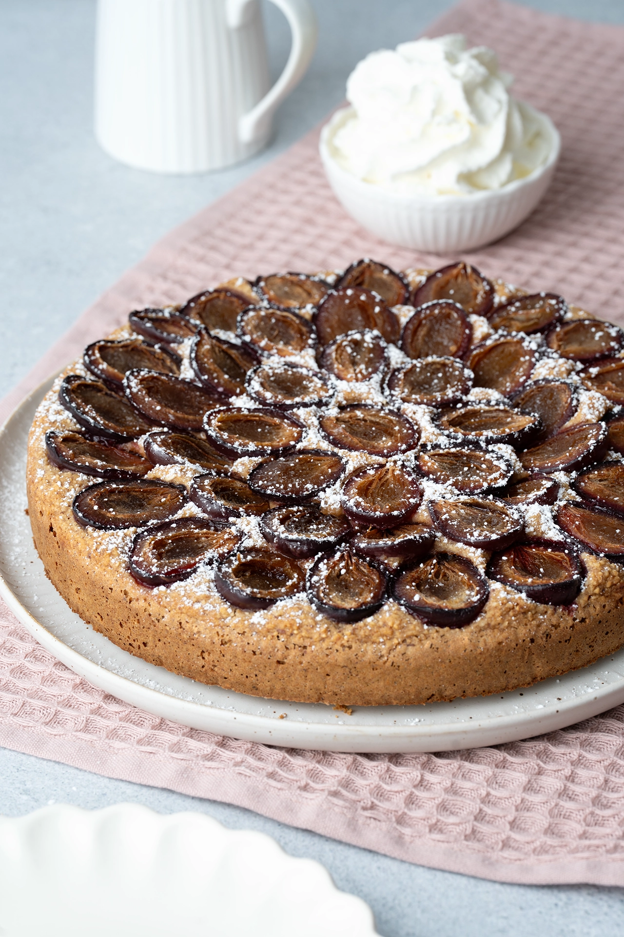 Gesunder Pflaumenkuchen (vegan, glutenfrei und zuckerfrei) 1 Gesunder Pflaumenkuchen auf weißer Platte auf rosa Tuch
