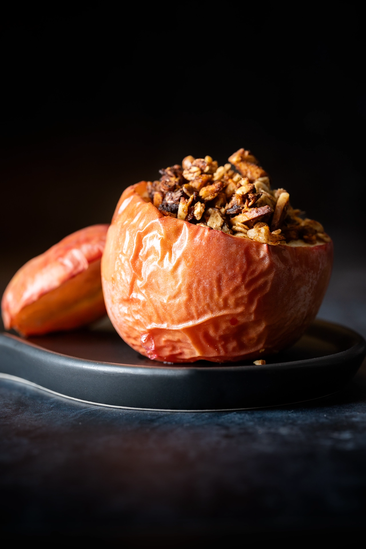 Veganer Bratapfel gefüllt auf einem schwarzem Teller