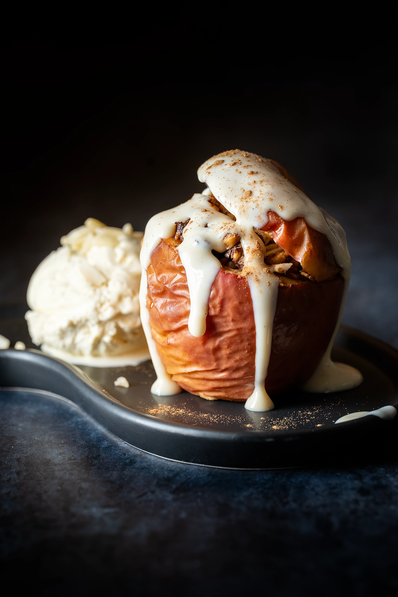 Bratapfel mit Vanilleeies und veganer Vanillesoße auf schwarzem Teller