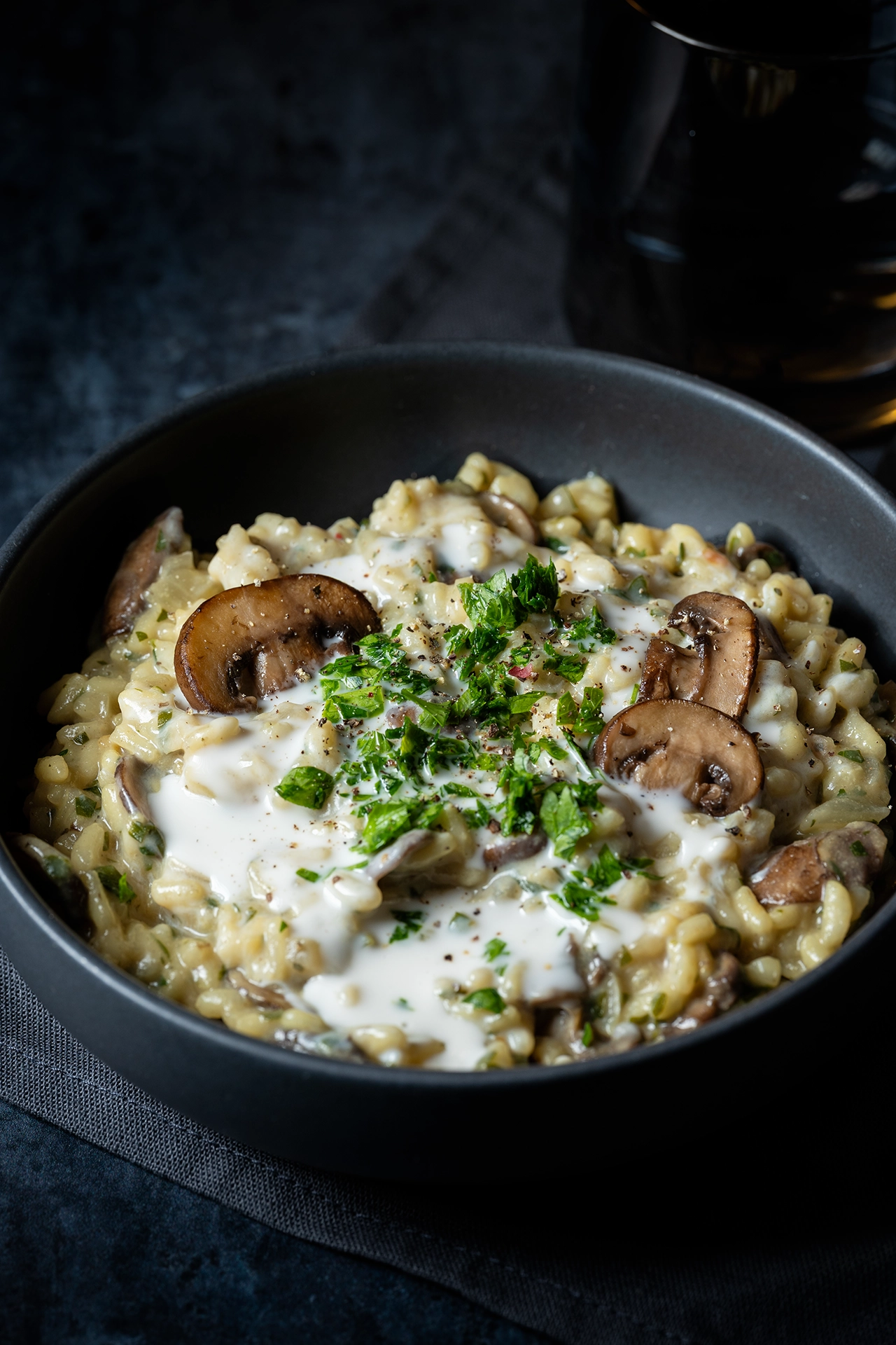 Pilzrisotto mit Champignons und Petersilie in schwarzer Schale