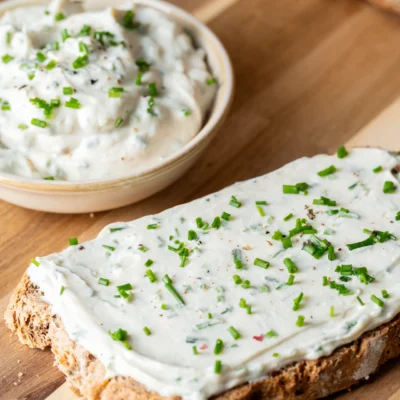 Veganer Frischkäse auf einer Scheibe Brot und in einer Schale