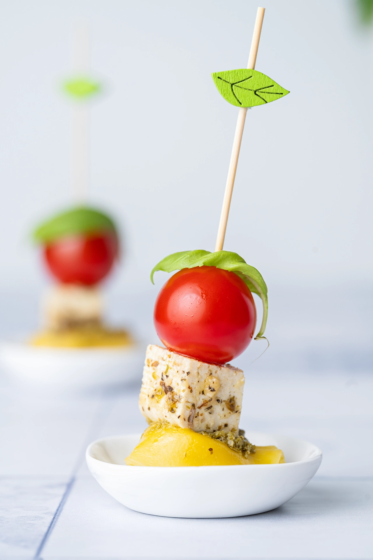 Tortellini-Spieß mit Tomate, Feta und Pesto auf einem kleinen Teller