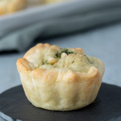 Vegane Mini-Quiches mit Blätterteig und Spinat auf einer kleinen schwarzen Platte