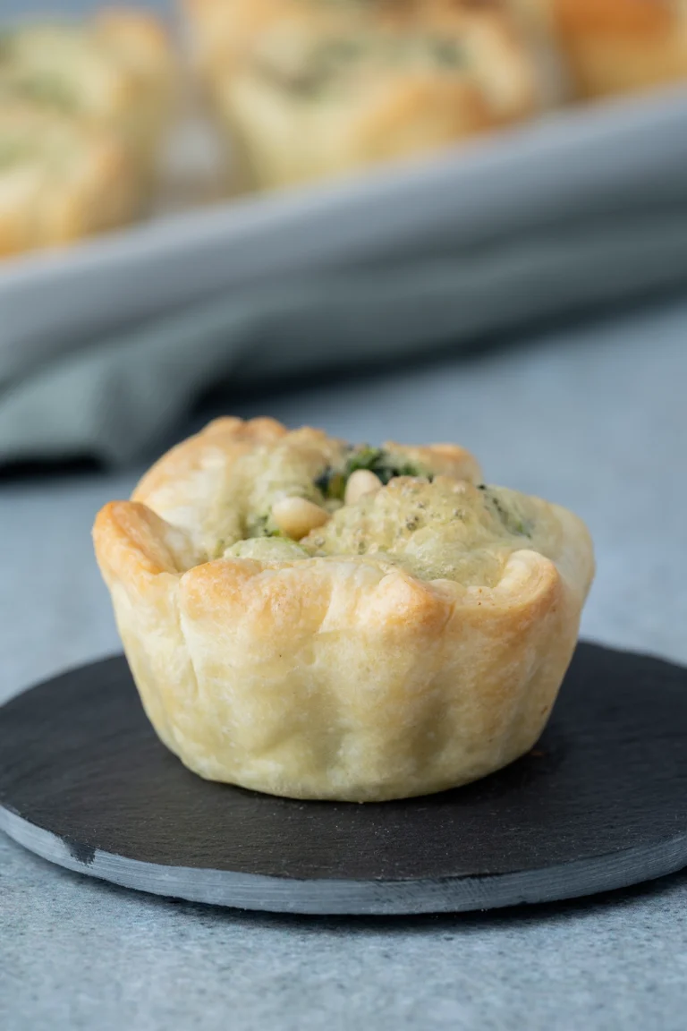 Vegane Mini-Quiches mit Blätterteig und Spinat auf einer kleinen schwarzen Platte