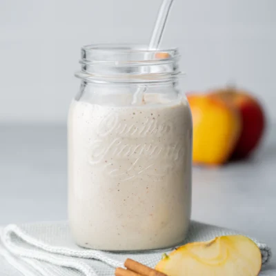 Winter-Smoothie im Glas daneben ein Apfel und Zimt