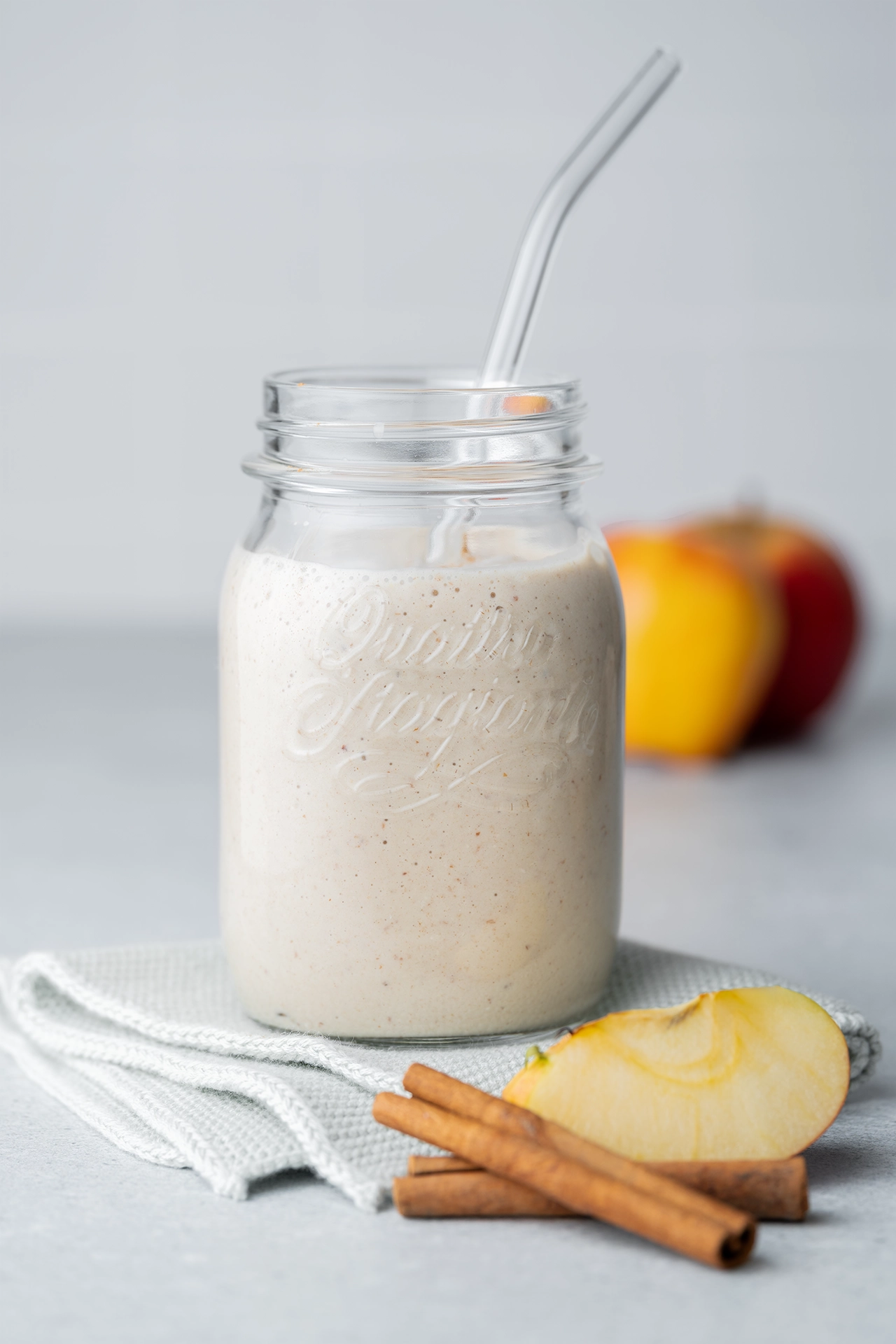 Winter-Smoothie im Glas daneben ein Apfel und Zimt