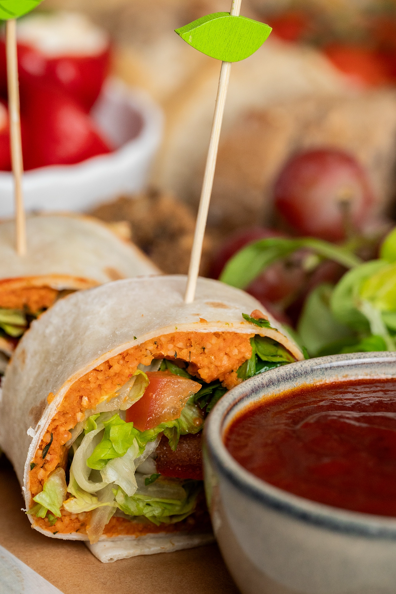 Cigköfte-Wrap geschnitten neben einer Schale mit Soße 