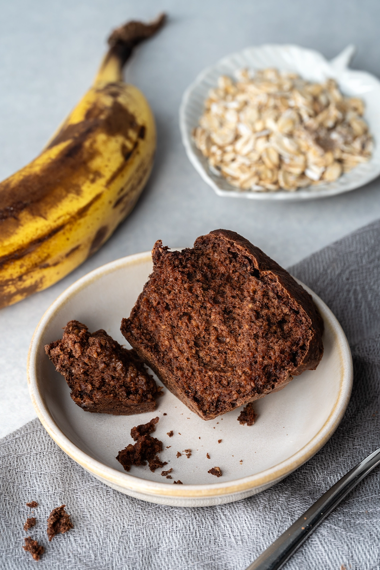 angebrochener Muffun auf einem Teller mit Banane und Haferflocken 
