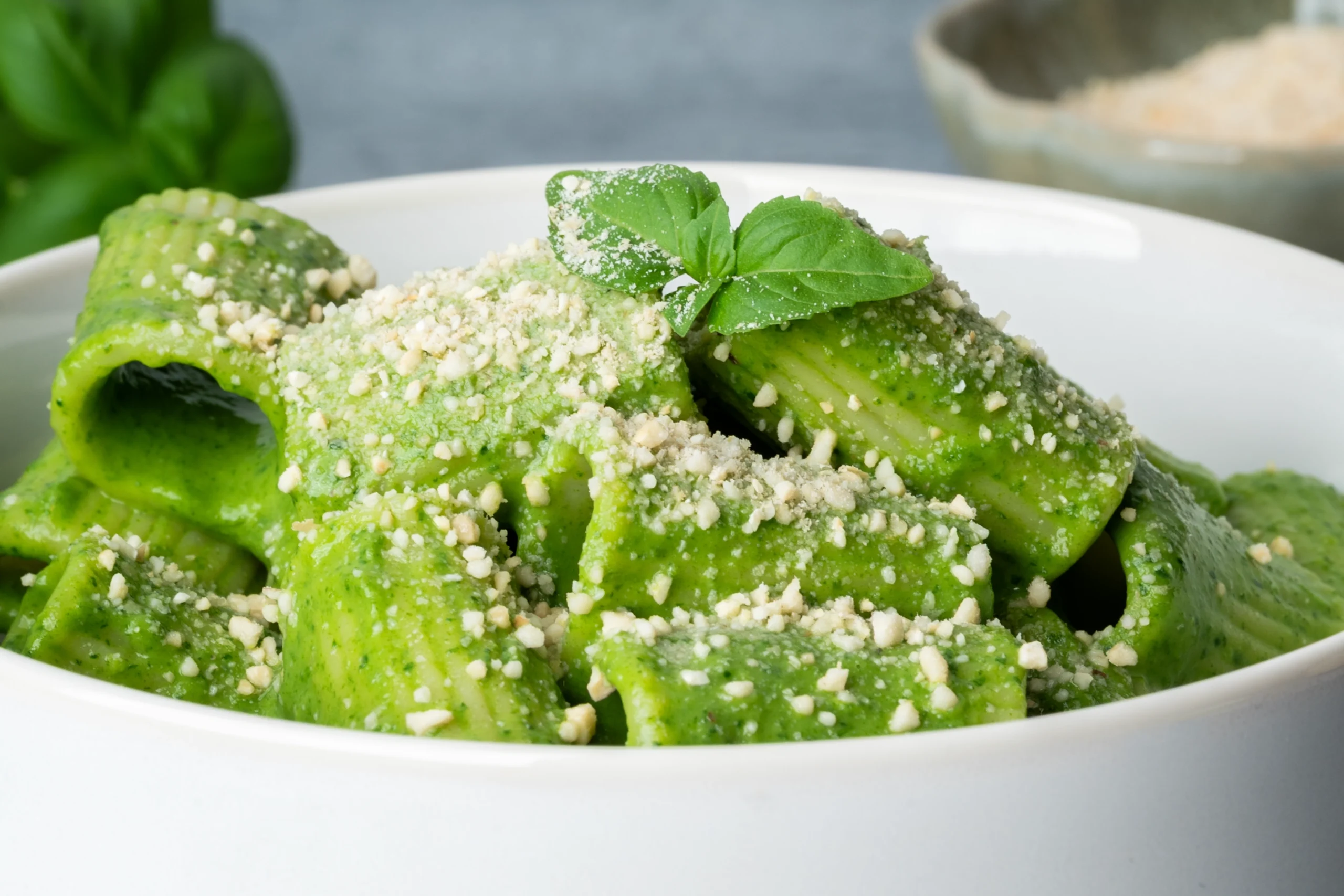 Green Goddess Pasta 3 Nudeln mit grüner Soße, veganem Parmesan und etwas frischem Basilikum in einer weißen Schale