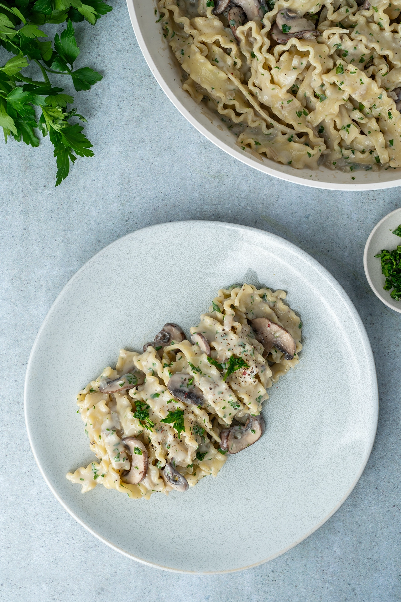 Champignon Pasta auf einem Teller und in einer Pfanne mit Petersilie