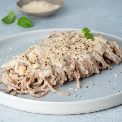 Vegane Spaghetti Carbonara auf hellem Teller mit Bsilikum