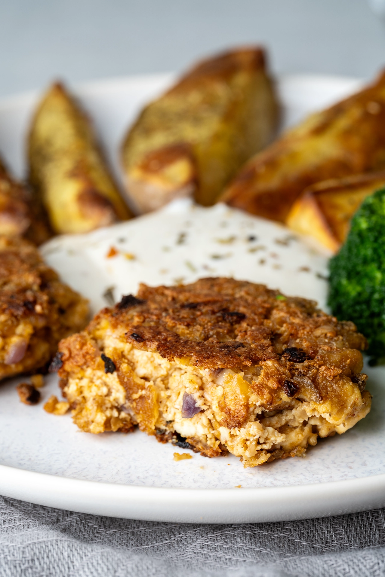 Vegane Frikadelle mit Tofu aufgeschnitten mit Quark und Kartoffeln auf einem Teller