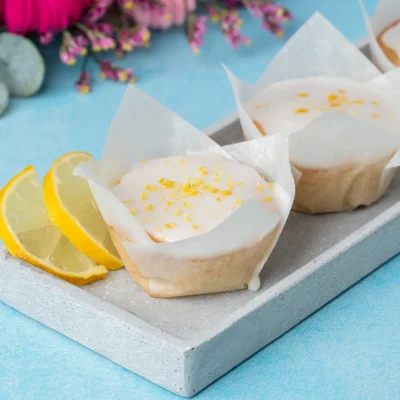 vegane Zitronenmuffins mit Zuckerguss auf blauem Untergrund