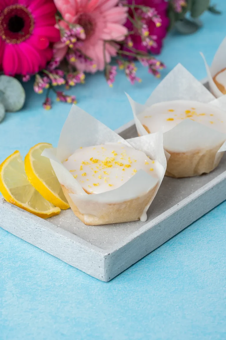 vegane Zitronenmuffins mit Zuckerguss auf blauem Untergrund