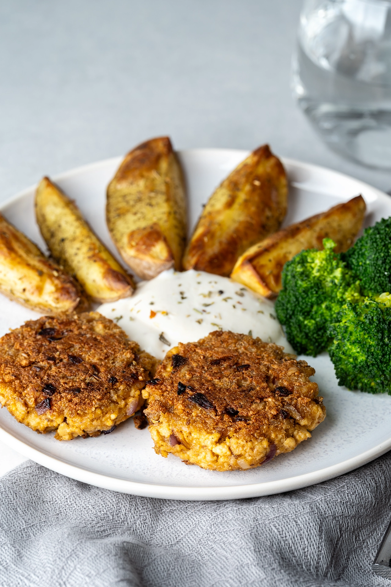 Vegane Frikadellen mit Kartoffeln, Brokkoli und Quark auf einem weißen Teller
