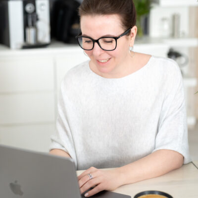 Katja am Laptop daneben eine Tasse Kaffee