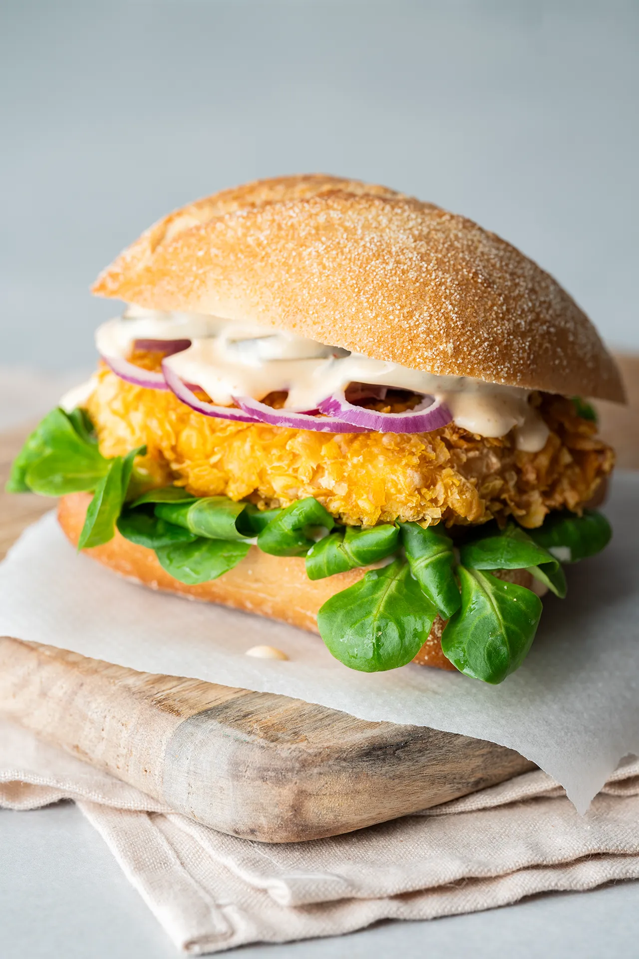 Crispy Tofu Sandwich – knusprig, würzig und richtig sättigend 1 Crispy Tofu Sandwich auf Backpapier auf einem Brett