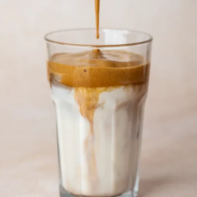 Einfacher Eiskaffee mit Instantkaffee in einem Glas beim Eingießen