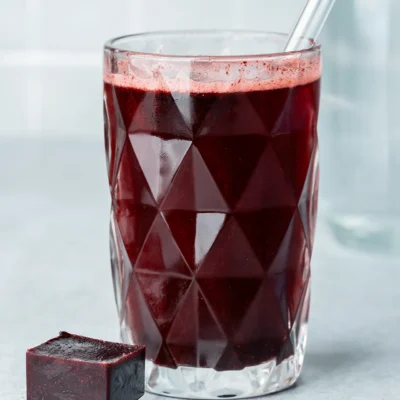 Heidelbeer-Eiswürfel in und neben einem Glas