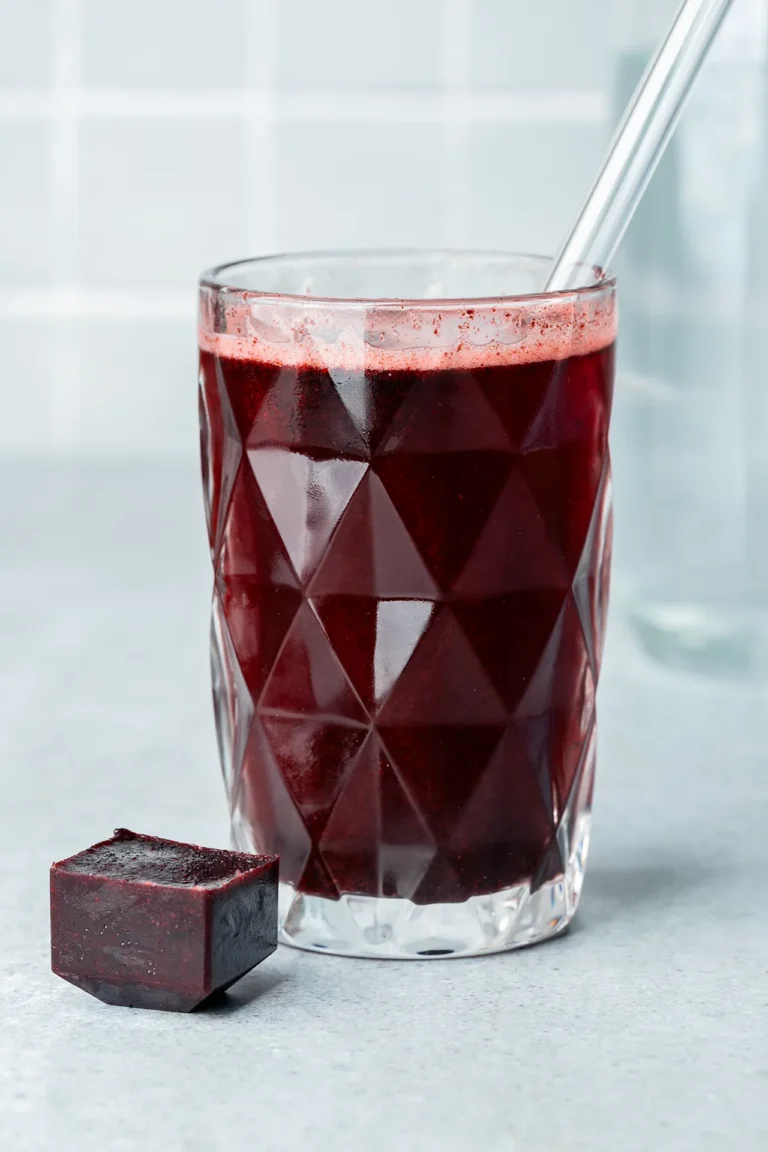Heidelbeer-Eiswürfel in und neben einem Glas