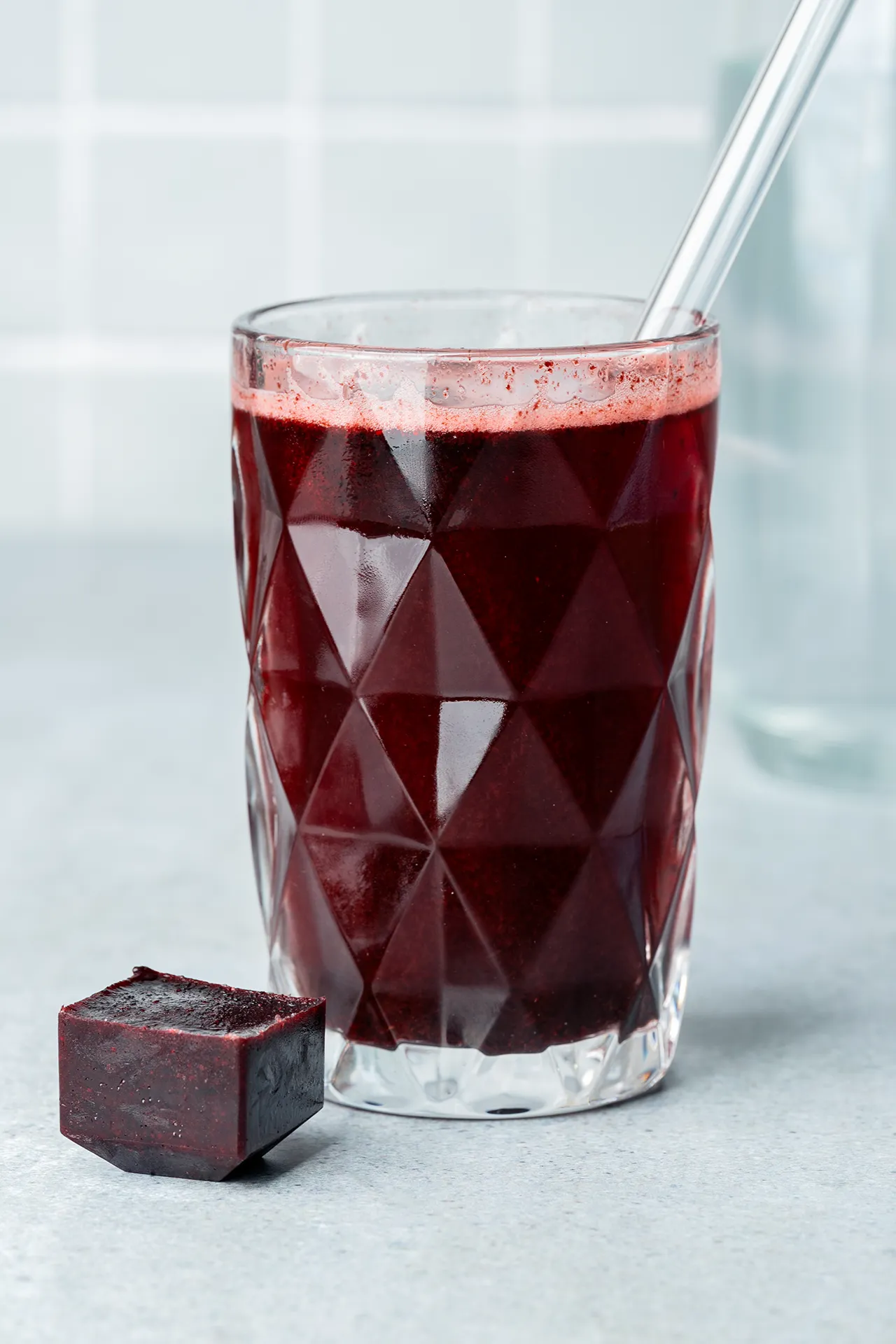 Heidelbeer-Eiswürfel in und neben einem Glas