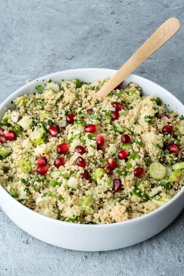 rezept-vegan-couscous-salat-minze-zitrone Couscous-Salat mit Kräutern, Zitrone und Granatapfelkernen in einer weißen Schale mit Holzlöffel